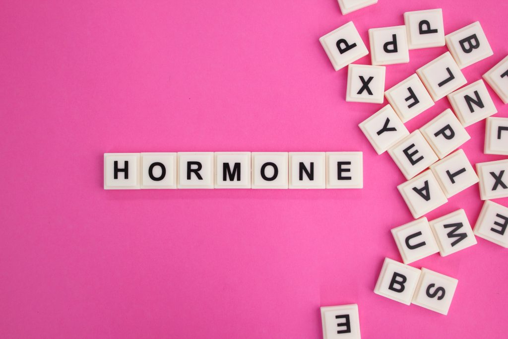 Mot hormone formé avec des lettres sur un fond rose, symbolisant les troubles hormonaux à Bourgoin
